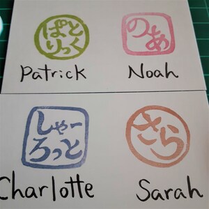 May include: Four white cards with Japanese characters and names written below. The characters are in green, pink, blue, and orange. The names are Patrick, Noah, Charlotte, and Sarah.