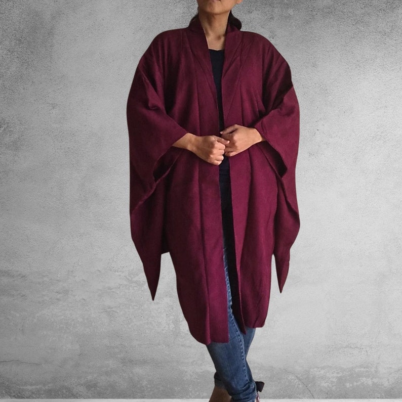 May include: A long, burgundy cardigan with a shawl collar and long sleeves. The cardigan is open in the front and has a relaxed fit.