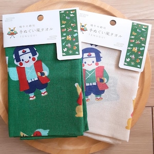 以下が含まれることがあります： 端午の節句のテーマの緑とクリーム色の手ぬぐい風タオル2枚。タオルには「端午の節句 手ぬぐい風タオル TENUGUI」の文字が印刷されています。