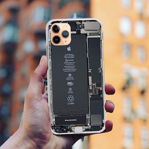 May include: A transparent back cover for an iPhone reveals the internal components, including the battery, camera, and motherboard. The battery label reads "Li-Ion Battery 3.82V 10.78Wh Apple 826-00387-A".