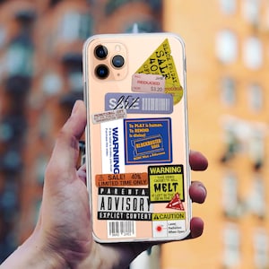 May include: A pink iPhone case with various colourful stickers. The stickers have text that reads "Black Friday Sale", "Warning", "To Play is human. To Rewind is divine", "Blockbuster Video", "Sale! 40% Limited Time Only", "Parental Advisory Explicit Content", "Warning This Video Cassette Will Melt If Left In The Car Or In The Sun", and "Caution Laser Radiation When Open".