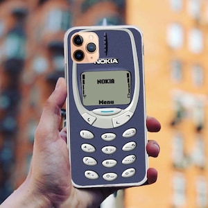 May include: A blue and white iPhone case with a Nokia phone design. The case has a black and white screen with the text "NOKIA" and "Menu". The case has a number pad with the numbers 1 through 9, a star, a pound sign, and a zero.
