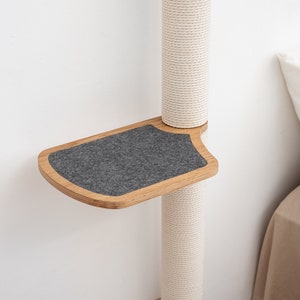 Pode incluir: Uma &aacute;rvore para gatos de madeira com uma plataforma de feltro cinza presa ao lado. A &aacute;rvore &eacute; envolvida em corda branca e est&aacute; contra uma parede branca.