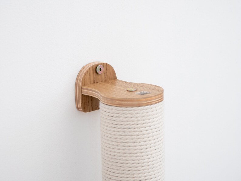 Pode incluir: Um poste de arranhar para gatos de madeira com uma cobertura de corda natural. O poste &eacute; montado em uma parede com um suporte de madeira. O suporte tem um parafuso e uma arruela.