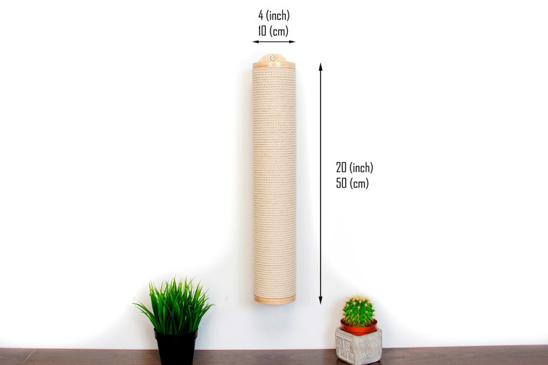 May include: A beige sisal scratching post for cats, mounted on a white wall. The post is 20 inches (50 cm) tall and 4 inches (10 cm) in diameter. There are two small potted plants on the floor below the post.