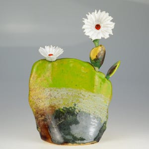 Peut inclure: Sculpture en céramique artisanale représentant un cactus avec deux fleurs blanches en forme de marguerite à centre rouge. La sculpture est principalement vert citron avec des accents marron, noir et jaune. Forme organique texturée.