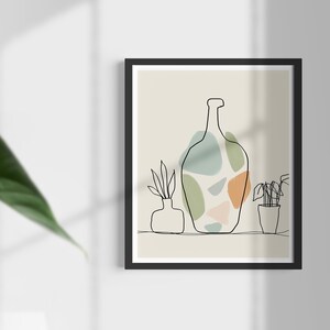 May include: A framed art print with a minimalist line drawing of a bottle and potted plants. The bottle design incorporates abstract shapes in green, orange, and blue. The artwork is set against a neutral background.