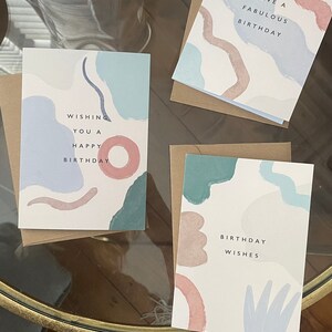May include: Three birthday cards with abstract pastel designs. Each card features a different message: "Wishing you a happy birthday," "Have a fabulous birthday," and "Birthday wishes."