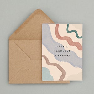 May include: A birthday card featuring abstract watercolour designs in blue, pink, and green, with a brown envelope. The card has the text "Have a Fabulous Birthday" in black.