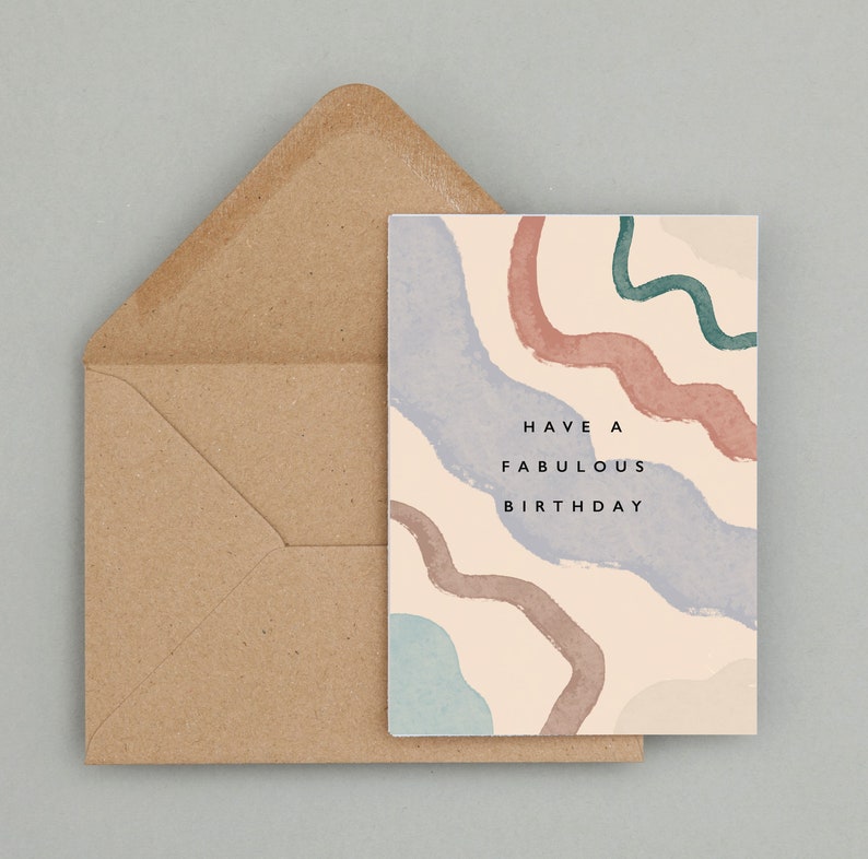 May include: A birthday card featuring abstract watercolour designs in blue, pink, and green, with a brown envelope. The card has the text "Have a Fabulous Birthday" in black.