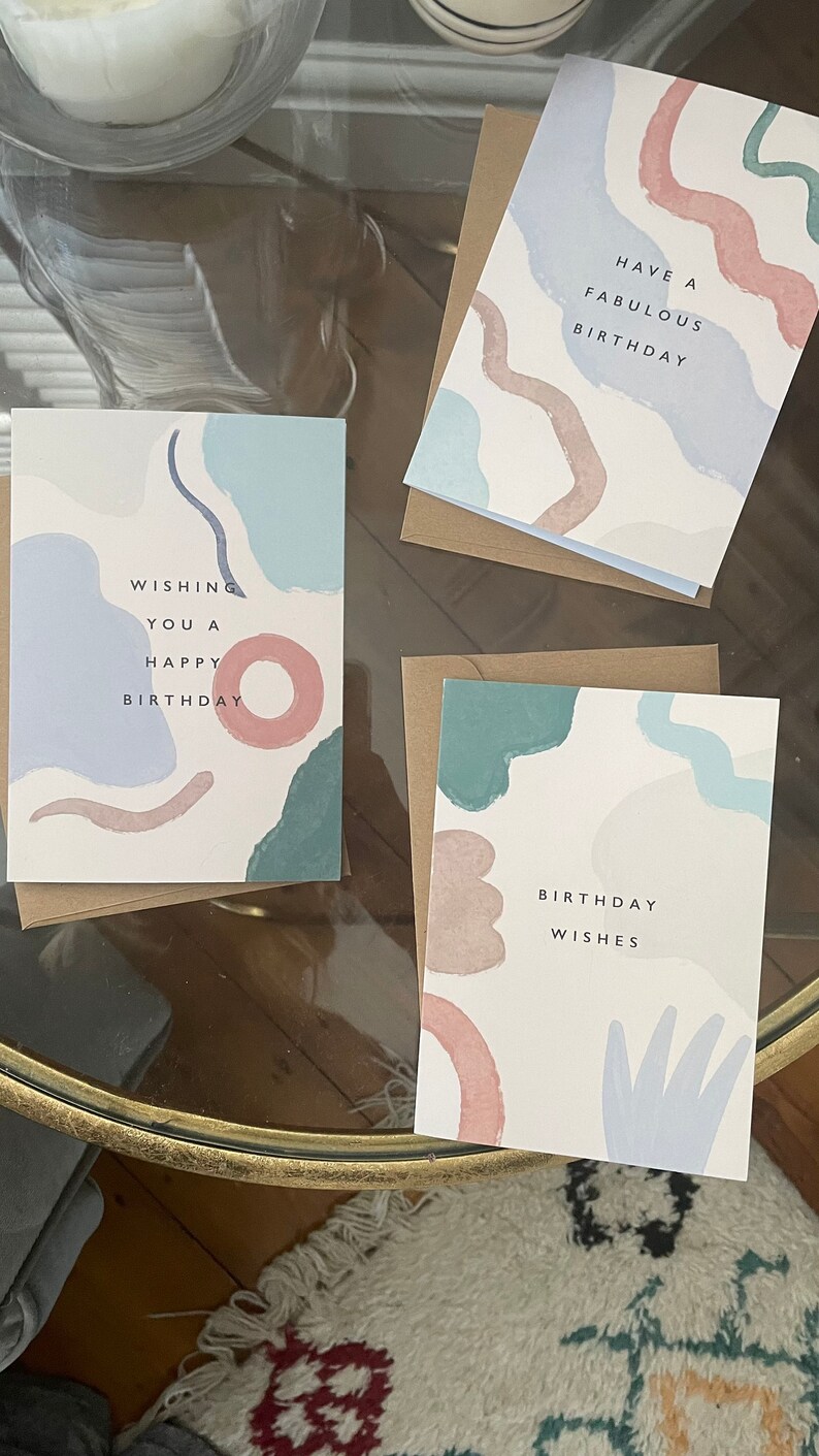 May include: Three birthday cards with abstract pastel designs. Each card has a brown envelope. The cards feature phrases such as "Wishing You a Happy Birthday" and "Have a Fabulous Birthday."