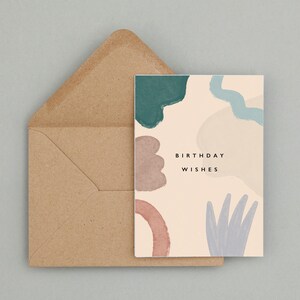 May include: A birthday card featuring abstract watercolour shapes in teal, mauve, and blue on a cream background. The card reads "BIRTHDAY WISHES" in black text, accompanied by a brown envelope.