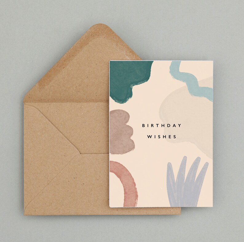 May include: A birthday card featuring abstract watercolour shapes in teal, mauve, and blue on a cream background. The card reads "BIRTHDAY WISHES" in black text, accompanied by a brown envelope.