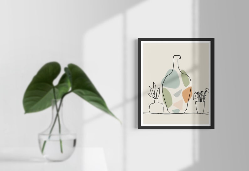 May include: A framed art print with a minimalist line drawing of a bottle and potted plants. The bottle design incorporates abstract shapes in green, orange, and blue. The artwork is set against a neutral background.