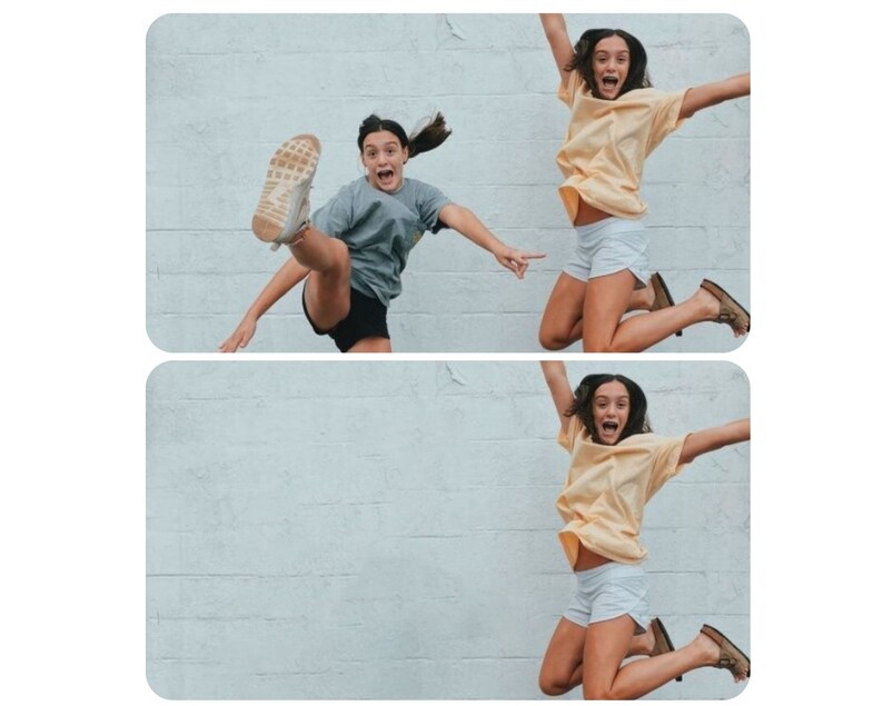 May include: Two people are jumping in the air in front of a white brick wall. The person on the left is wearing a grey shirt, black shorts, and white sneakers. The person on the right is wearing a yellow shirt, white shorts, and brown sandals.