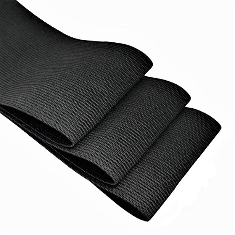May include: Three rolls of black elastic fabric, folded and stacked on top of each other. The fabric has a textured, woven appearance.