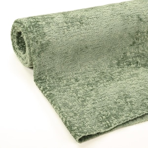 May include: A rolled-up section of sage green fabric. The material has a textured, plush appearance, with a slightly uneven surface. The fabric is likely a soft material, possibly for upholstery or decorative purposes.