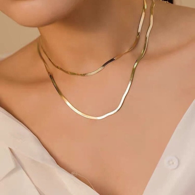 Puede incluir: Un collar de cadena de oro con un delicado dise&ntilde;o de cadena de serpiente plana. El collar est&aacute; formado por dos cadenas de diferentes longitudes.