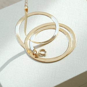 Puede incluir: Un collar de cadena de serpiente de dos tonos, dorado y plateado, con cierre de mosquet&oacute;n.