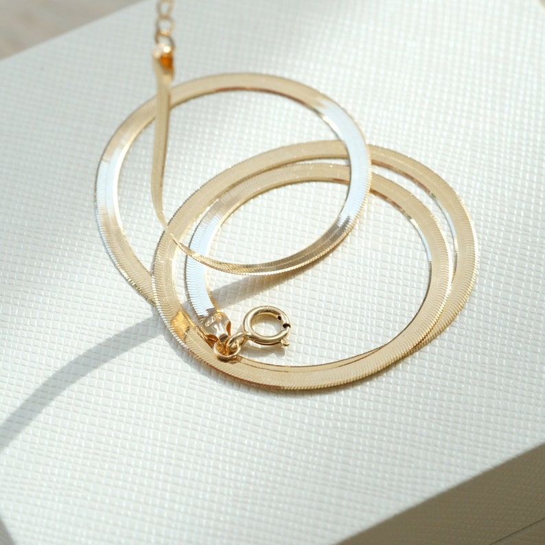 Puede incluir: Un collar de cadena de serpiente de dos tonos, dorado y plateado, con cierre de mosquet&oacute;n.