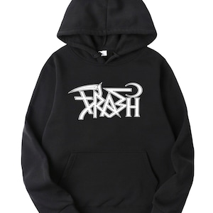 May include: Black hooded sweatshirt with a white graphic that says "TRASH" in a stylized font. The sweatshirt has a front pocket and a drawstring hood. The design features a scythe and a star.