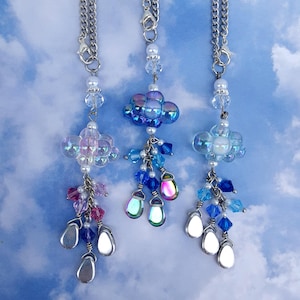 May include: Three silver chain necklaces with iridescent blue and white cloud charms and crystal raindrop accents.