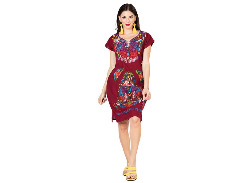 May include: A maroon short-sleeved dress with colorful embroidery featuring a floral design. The dress has a v-neck and a loose fit.