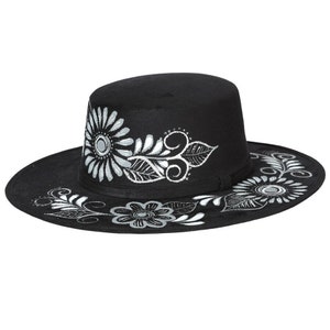 May include: A black fedora hat with a white floral design. The hat has a wide brim and a tall crown.