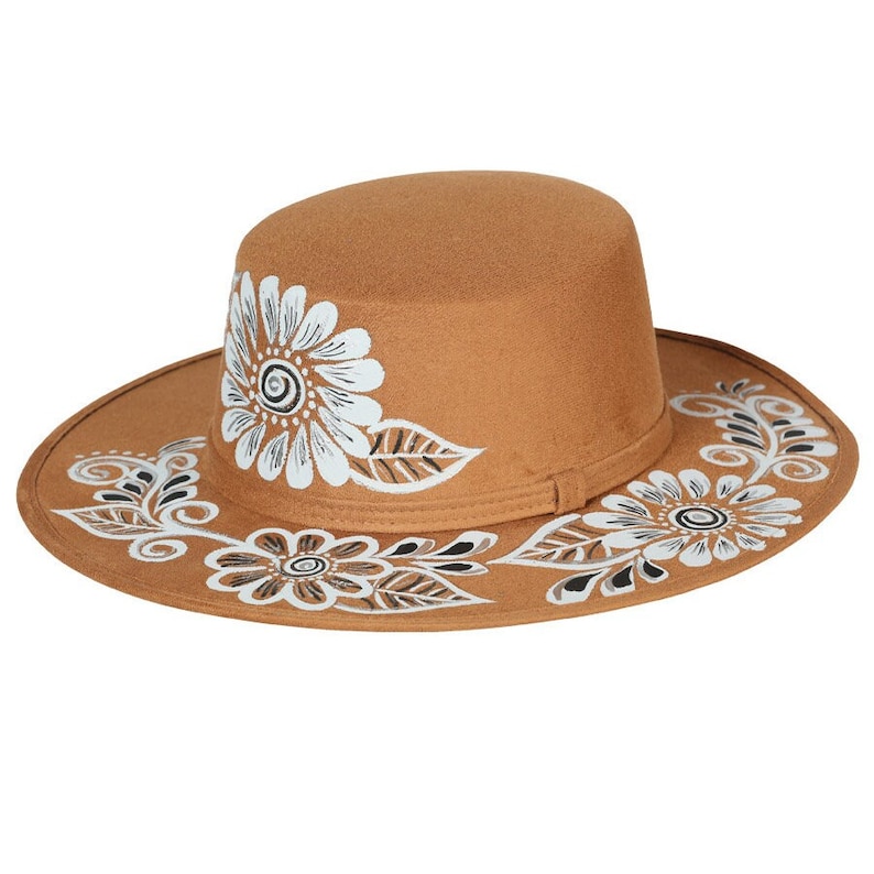 May include: A brown felt fedora hat with white and black floral designs painted on the brim and crown.