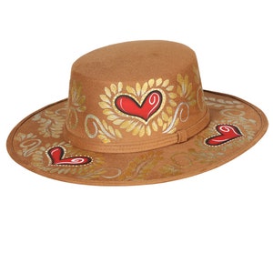 May include: A brown felt hat with a wide brim and a flat crown. The hat is decorated with gold leaf and red hearts.