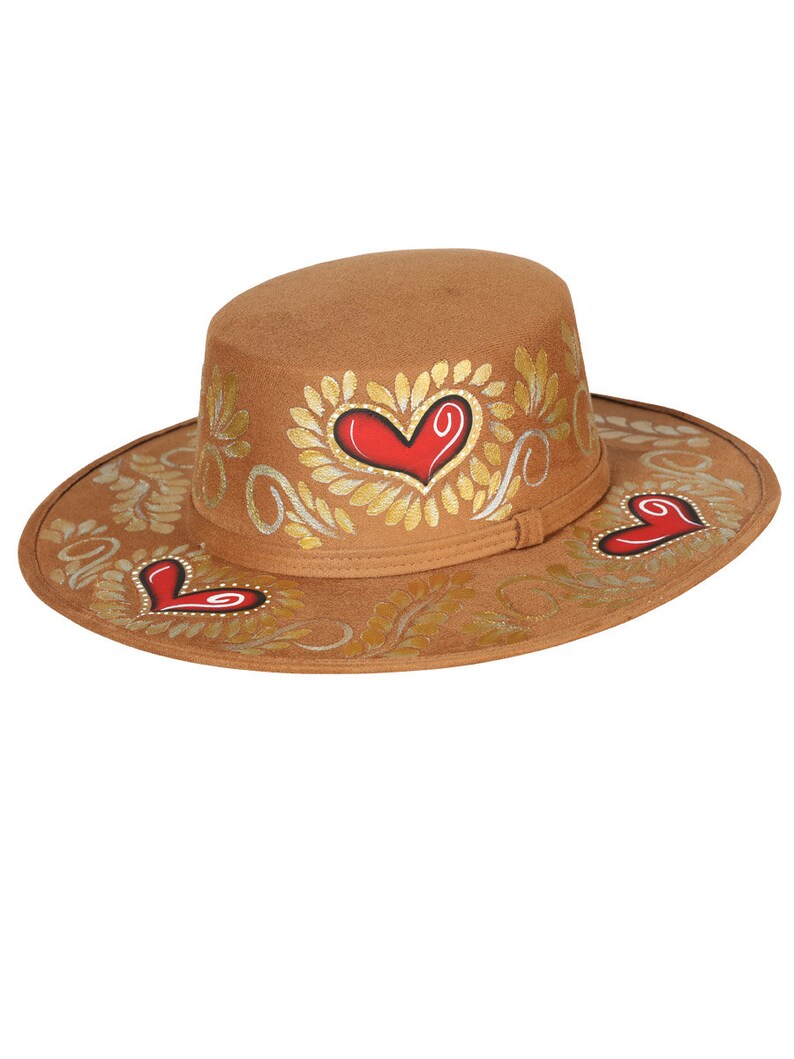 May include: A brown felt hat with a wide brim and a flat crown. The hat is decorated with gold leaf and red hearts.