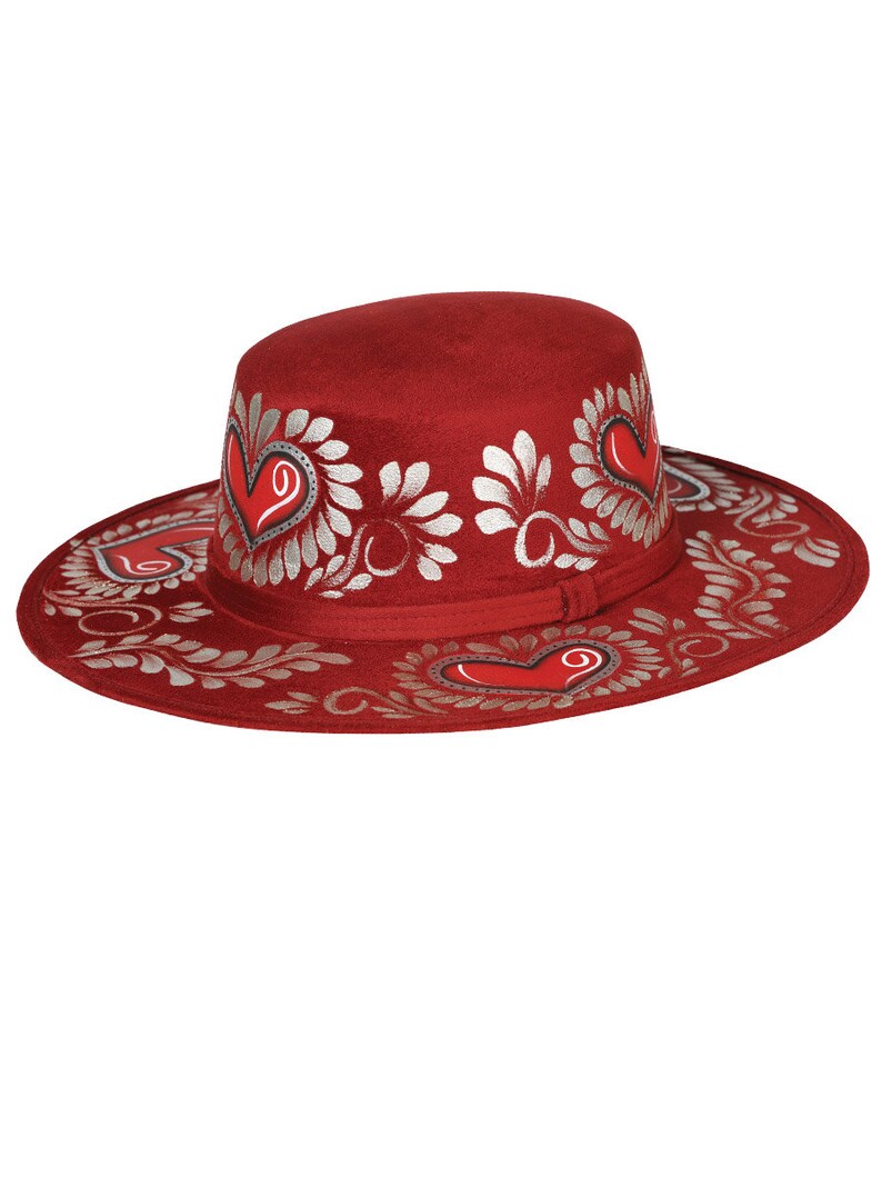 May include: A red felt hat with a wide brim and silver painted floral designs and hearts.