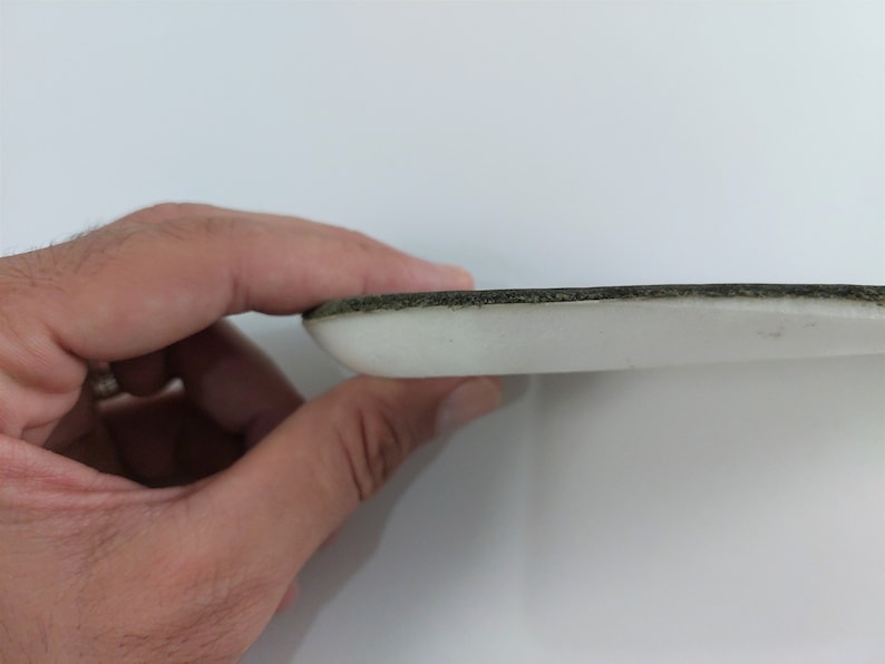 May include: Close-up of the edge of a white foam insole with a black trim.