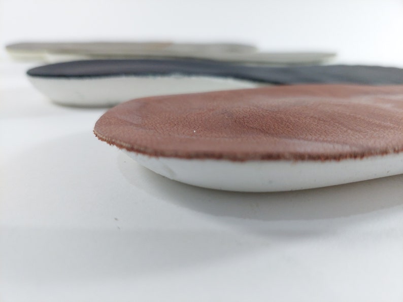 May include: Close-up of a brown leather insole with a white foam base. The insole is designed to provide comfort and support for the feet.