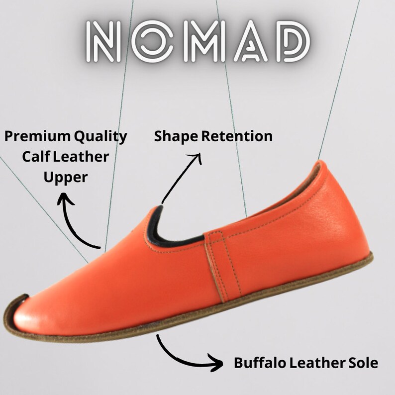 May include: A bright orange leather slipper with a black leather trim around the opening. The sole is made of brown buffalo leather. The text "NOMAD" is visible in the upper left corner of the image. The text "Premium Quality Calf Leather Upper" is visible in the upper left corner of the image. The text "Shape Retention" is visible in the upper right corner of the image. The text "Buffalo Leather Sole" is visible in the lower right corner of the image.