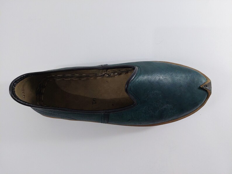 May include: A pair of teal blue leather slippers with a pointed toe and a brown sole.