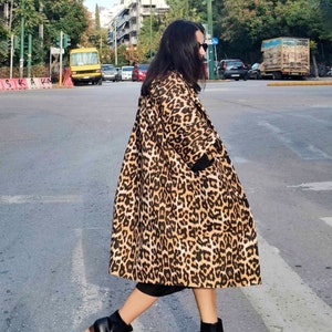Könnte beinhalten: Eine Frau trägt einen langen Leopardenfellmantel mit schwarzen Stiefeletten. Die Stiefeletten haben einen Holzabsatz.