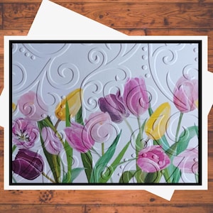 May include: A greeting card featuring a bouquet of colorful tulips with a white background and a decorative embossed pattern. The tulips are in shades of pink, purple, yellow, and white.