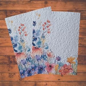 Puede incluir: Tres tarjetas blancas con un patr&oacute;n floral. Las tarjetas tienen un dise&ntilde;o en relieve con un patr&oacute;n floral. Las flores son en tonos de azul, rosa y amarillo.