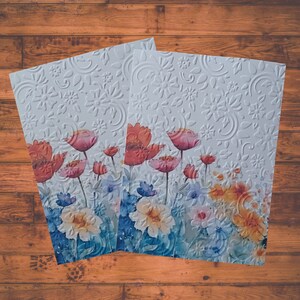 Puede incluir: Dos tarjetas blancas con un dise&ntilde;o floral. Las tarjetas presentan flores de acuarela en tonos de rosa, rojo y azul. El fondo es un patr&oacute;n en relieve blanco.