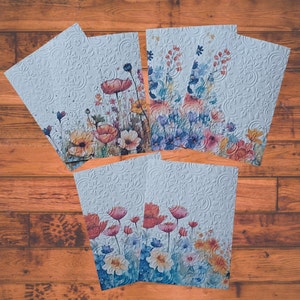 Puede incluir: Conjunto de seis tarjetas blancas con un patr&oacute;n floral en relieve y dise&ntilde;os florales de acuarela. Las tarjetas presentan una variedad de flores en tonos de azul, rosa, amarillo y naranja.