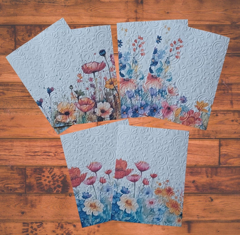 Puede incluir: Conjunto de seis tarjetas blancas con un patr&oacute;n floral en relieve y dise&ntilde;os florales de acuarela. Las tarjetas presentan una variedad de flores en tonos de azul, rosa, amarillo y naranja.