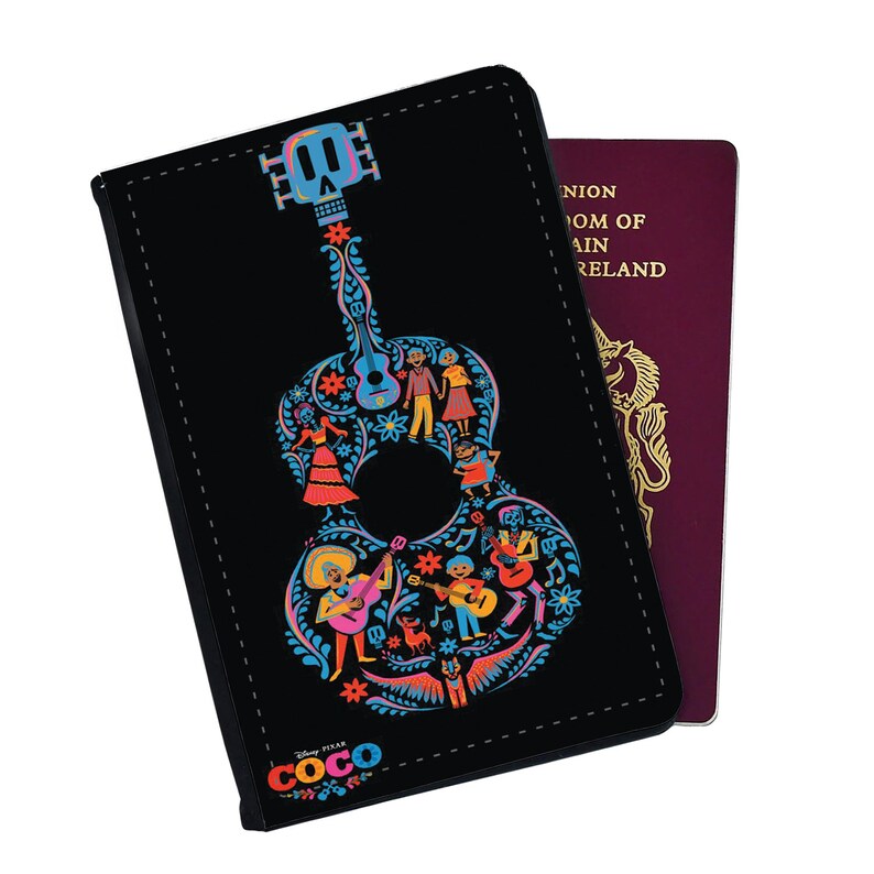 May include: Black passport holder with a colorful guitar design featuring characters from the Disney Pixar movie Coco. The guitar is decorated with flowers and musical notes. The text "Coco" is printed on the bottom of the holder.