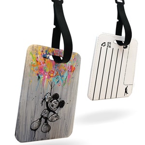 May include: A white luggage tag featuring a colourful cartoon image of Mickey Mouse holding balloons. The tag has a black strap and a blank white area for writing contact details.