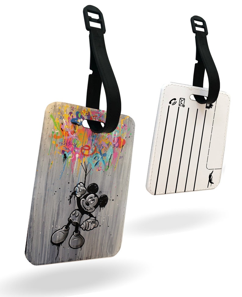 May include: A white luggage tag featuring a colourful cartoon image of Mickey Mouse holding balloons. The tag has a black strap and a blank white area for writing contact details.