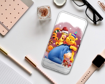 May include: A white phone case with a colorful illustration of Winnie the Pooh, Piglet, and Tigger wearing winter hats and holding presents. The background is a pink and white winter scene with snowflakes.
