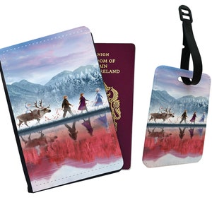 May include: A passport holder and luggage tag set featuring a winter scene with four figures walking on a frozen lake. The figures are walking in a line, with a reindeer and a snowman in front of them. The background is a snowy forest with mountains in the distance. The sky is a soft pink and blue.