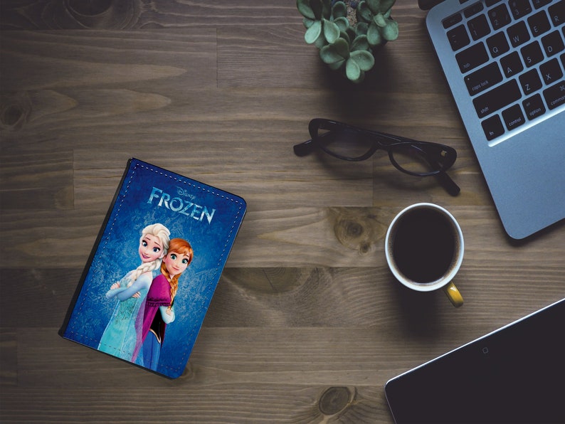 May include: A blue notebook with a Disney Frozen design featuring Elsa and Anna. The notebook has a stitched edge and the title "Disney Frozen" is printed on the cover.