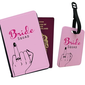 Puede incluir: Conjunto de portapasaporte y etiqueta de equipaje rosa con el texto "Bride Squad" y una mano de dibujos animados con un anillo en el dedo medio.