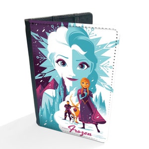 May include: A passport holder featuring a colorful illustration of Elsa and Anna from the Disney movie Frozen. The image shows the sisters standing in a snowy landscape with a castle in the background. The text "Frozen" is printed on the front of the holder.
